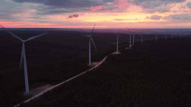 Windturbine boerderij op prachtige paarse avond berglandschap. Duurzame energieproductie voor een groene ecologische wereld. Luchtfoto van windmolens park park op de avond berg. — Stockvideo