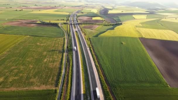 Autoroute avec circulation dans les paysages ruraux. Autoroute de banlieue avec voitures et camions. Voyage et transport. Vue aérienne — Video