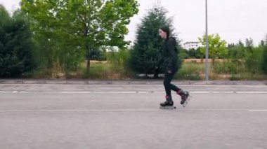 Atışı takip edin, yolda paten kayan genç bir kadının yan görüntüsü..