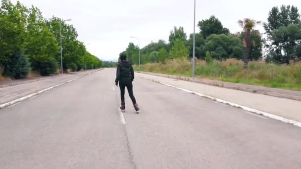 Seguir disparo, vista trasera de la joven mujer practicando patinaje sobre ruedas en la carretera . — Vídeos de Stock