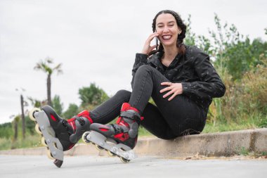 Paten kayan mutlu kadın, sokakta oturuyor ve cep telefonu kullanıyor. Güzel, Urban Girl telefonda konuşuyor, paten kayıyor. Şehirdeki Modern Kız 