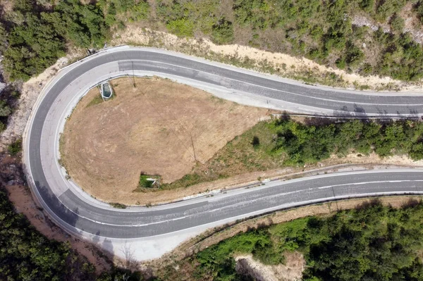 Vista aérea da estrada sinuosa em alta montanha passe através de pinheiros verdes . — Fotografia de Stock