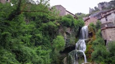 Ortaçağ köyü Orbaneja del Castillo 'da cennet gibi bir şelalenin sinematik görüntüsü. Burgos, İspanya 'nın ünlü turistik beldesi.