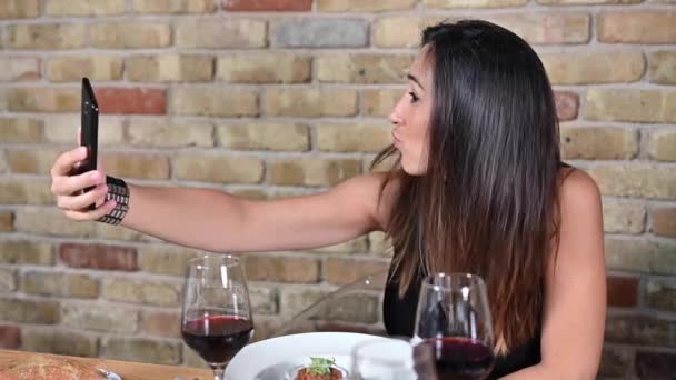 Красива молода жінка робить селфі фотографію під час їжі в ресторані . — стокове відео