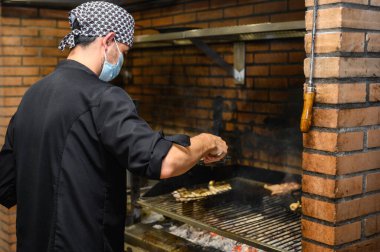 Şef ticari mutfakta biftek pişiriyor.