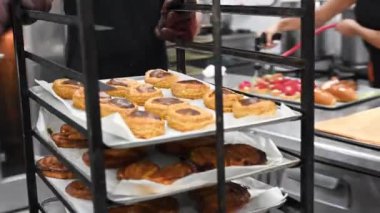 Koruyucu eldivenli fırıncı rafları farklı hamur işleriyle itiyor.. 