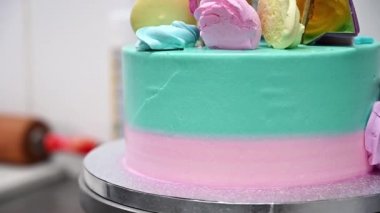 Tatlı ürünlerle süslenmiş güzel bir pasta tezgahın etrafında dönüyor. Arkaplanda şekerleme araçları.