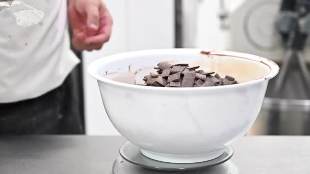 Pasticceria Lo chef aggiunge pezzi di cioccolato pronti a fondersi. Ingredienti della ricetta di una torta al cioccolato. — Video Stock