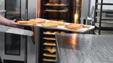 Pasta şefi tepsiyi fırına koyar..