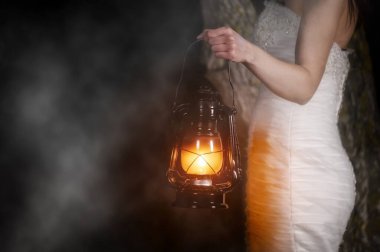 Gece vakti dışarıda Vintage Lantern 'i olan tanınmayan bir kadın. Beyaz uzun elbiseli genç bir kadın gece ormanında yürüyor..