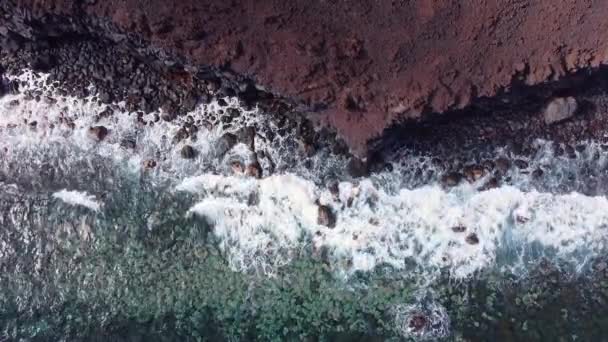 Kayalık volkanik kıyı şeridine uçan dalgaların yukarıdan görünüşü. Video Klip