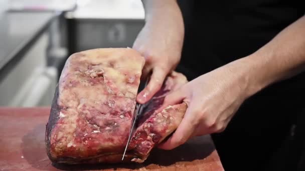 Surowy stek wołowy na drewnianej desce. Rzeźnik tnie surowe mięso nożem w zwolnionym tempie — Wideo stockowe