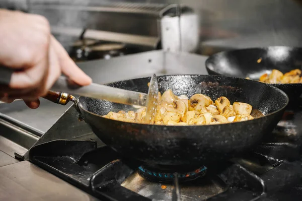 Chef cooking mushrooms in frying pan on burning fire. — Stock Photo, Image