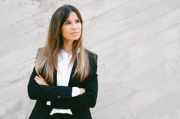 Portrait of businesswoman leader with serious expression standing with arm crossed.