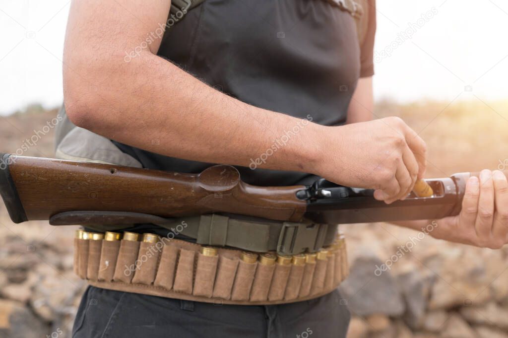Close up of an unrecognizable hunter, loading shotgun, holds a shotgun and ammunition in his hand.