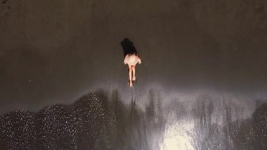 Kumlu sahilde oturan tanınmayan genç kadın kıyı şeridi dalgaları, hava manzarası....