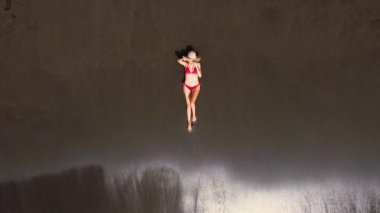 Plajda yatan tanınmayan genç bir kadının havadan görünüşü. Plajda güneş şapkası takan bronz tenli kadın. Sandy Tropikal Plajı.
