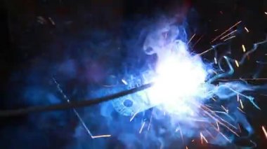 Kıvılcım saçan bir fabrikada kaynak yapan bir işçi.