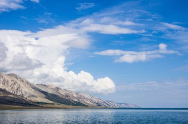Su, dağlar ve gökyüzü bulutlu. Boş alan