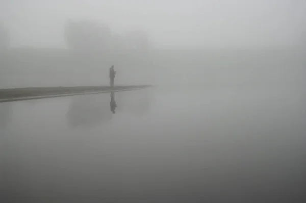 Nehir kıyısında bir siste yalnız balıkçı