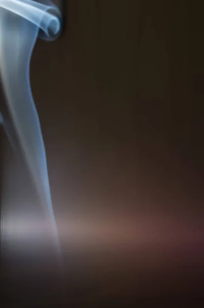 Duman karanlık bir arka plan üzerinde renkli damlama