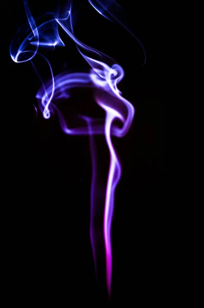 Duman karanlık bir arka plan üzerinde renkli damlama