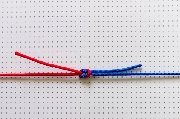 Bir düğüm üzerinde hafif bir arka plan ile kırmızı ve mavi ipler dokuma