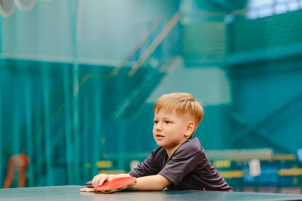 グレーの シャツで幸せな少年テニス ホールで卓球に立ち 前方に見える — ストック写真