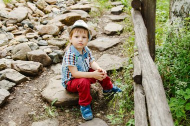 yakışıklı yakışıklı yaz aylarında bir taş yolu parkta oturan şapka ve kırmızı pantolon