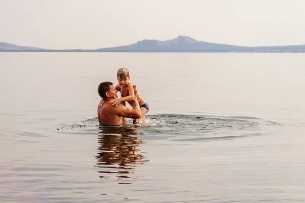 father teaches little son to swim in the lake