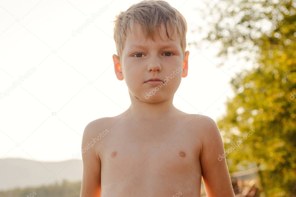 portrait of a stripped boy five years old on chest outdoors