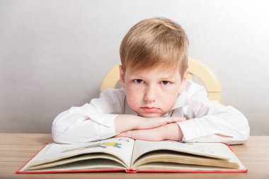 Üzgün çocuk masasında oturan beyaz gömlekli