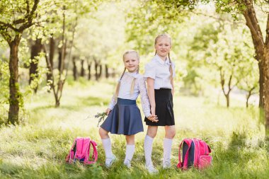 şirin sarışın kızlar okul üniforması, beyaz kurul ve sırt çantası soutdoors