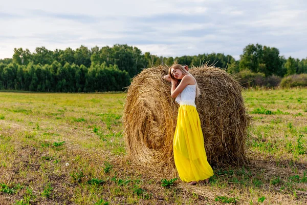 干し草の山の近くの長い黄色のスカートで美しい女性 — ストック写真