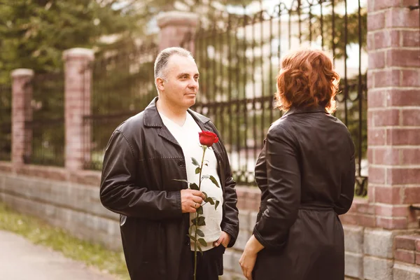 a middle-aged man gives a rose to a woman, romantic date