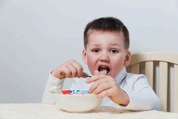 Criança Come Massa Uma Mesa Fundo Branco — Fotografia de Stock