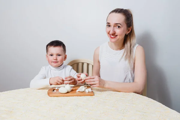妈妈和孩子在白色背景下的桌子上煮熟的鸡蛋 — 图库照片