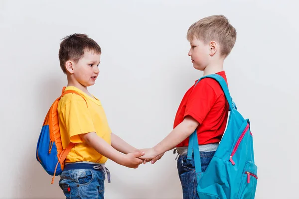 Два Мальчика Школьными Рюкзаками Держатся Руки Белом Фоне — стоковое фото