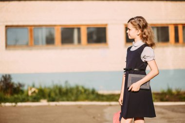 bir sırt çantası ve bir kitap ile şirin kız öğrenci okula gidiyor