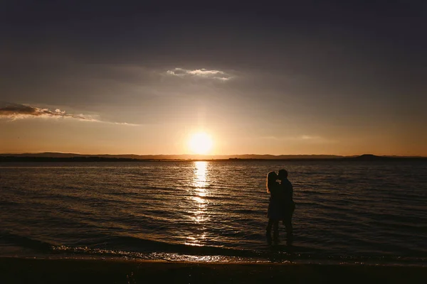 Silhouette couples in the sea at sunset, love