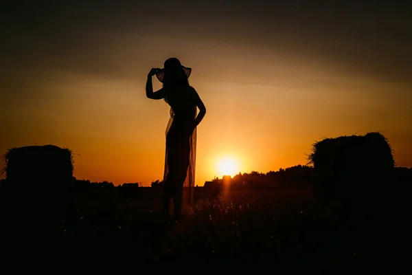 female silhouette at sunset, woman in hat