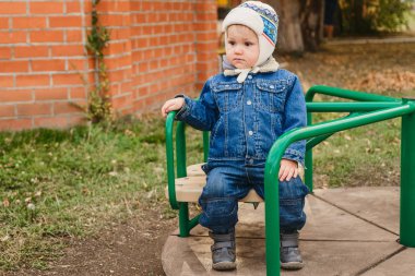 kot takım elbiseli küçük oğlu parkta, atlıkarınca üstünde dönen çocuk çalıyor.