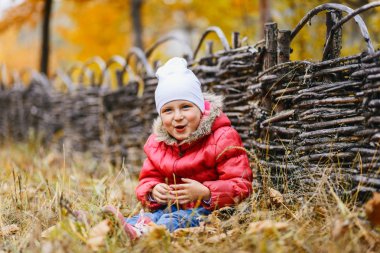 Kırmızı ceketli çit oturan sevimli kız
