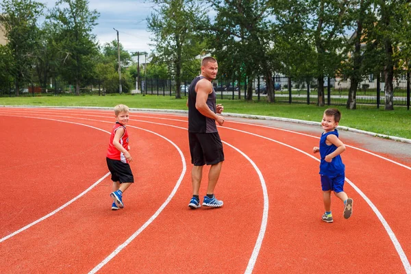 a man with two children run for sports stadium, happy family