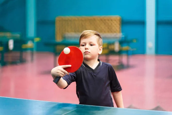 the child plays table tennis indoors