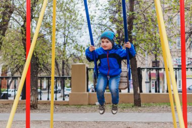 küçük bir çocuk parkta bir salıncak üzerinde sürme kot pantolon