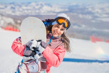 Kışın dağda snowboard ile mutlu gülümseyen genç kadın