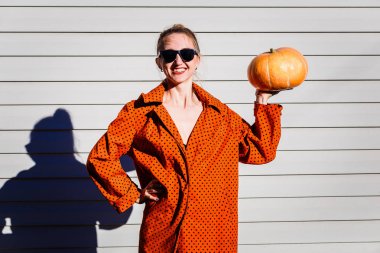 genç gülümseyen kadın koyu gözlüklü kabak güneş ışığı onun elinde tutan turuncu karnaval kılık