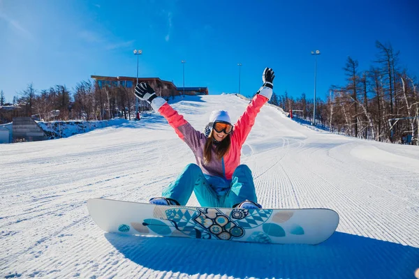 年轻的快乐妇女滑雪板坐在一个下雪的山坡上 — 图库照片