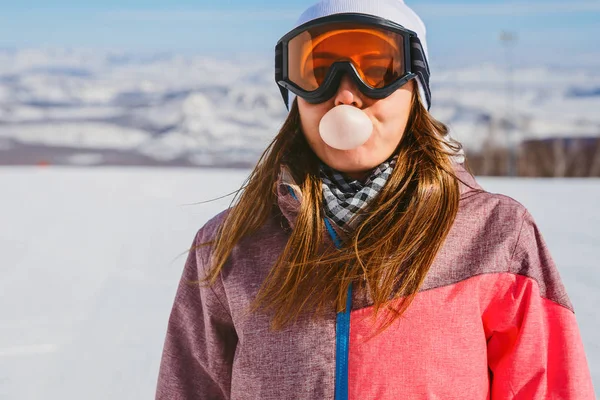 年轻妇女膨胀大气泡口香糖在山区冬季 — 图库照片